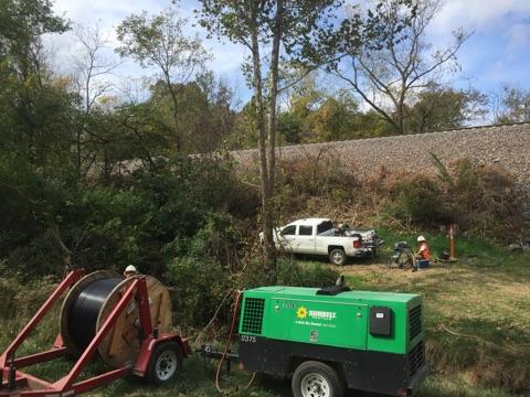 A green trailer with a generator attached to it is parked in a field.