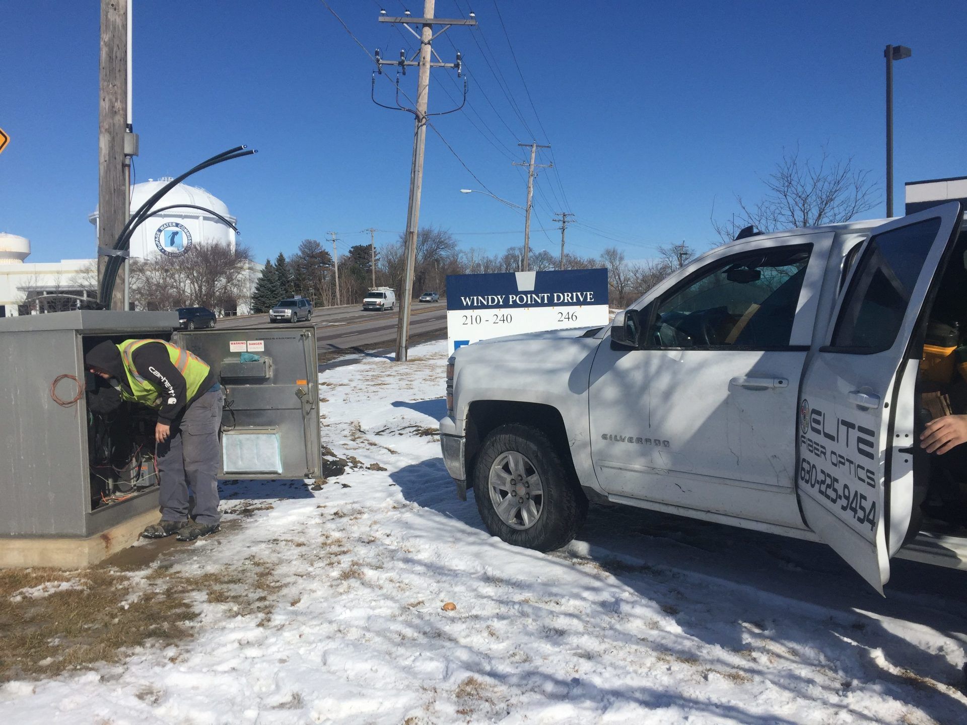 A man is standing next to a white truck in the snow.