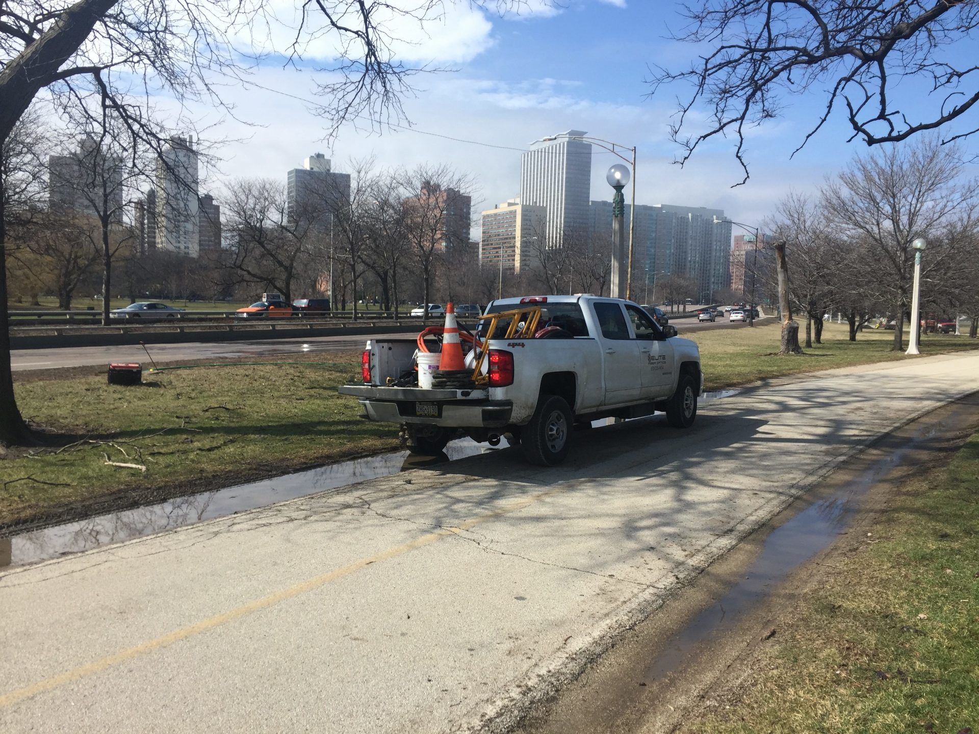 A white truck is parked on the side of a road in a park.