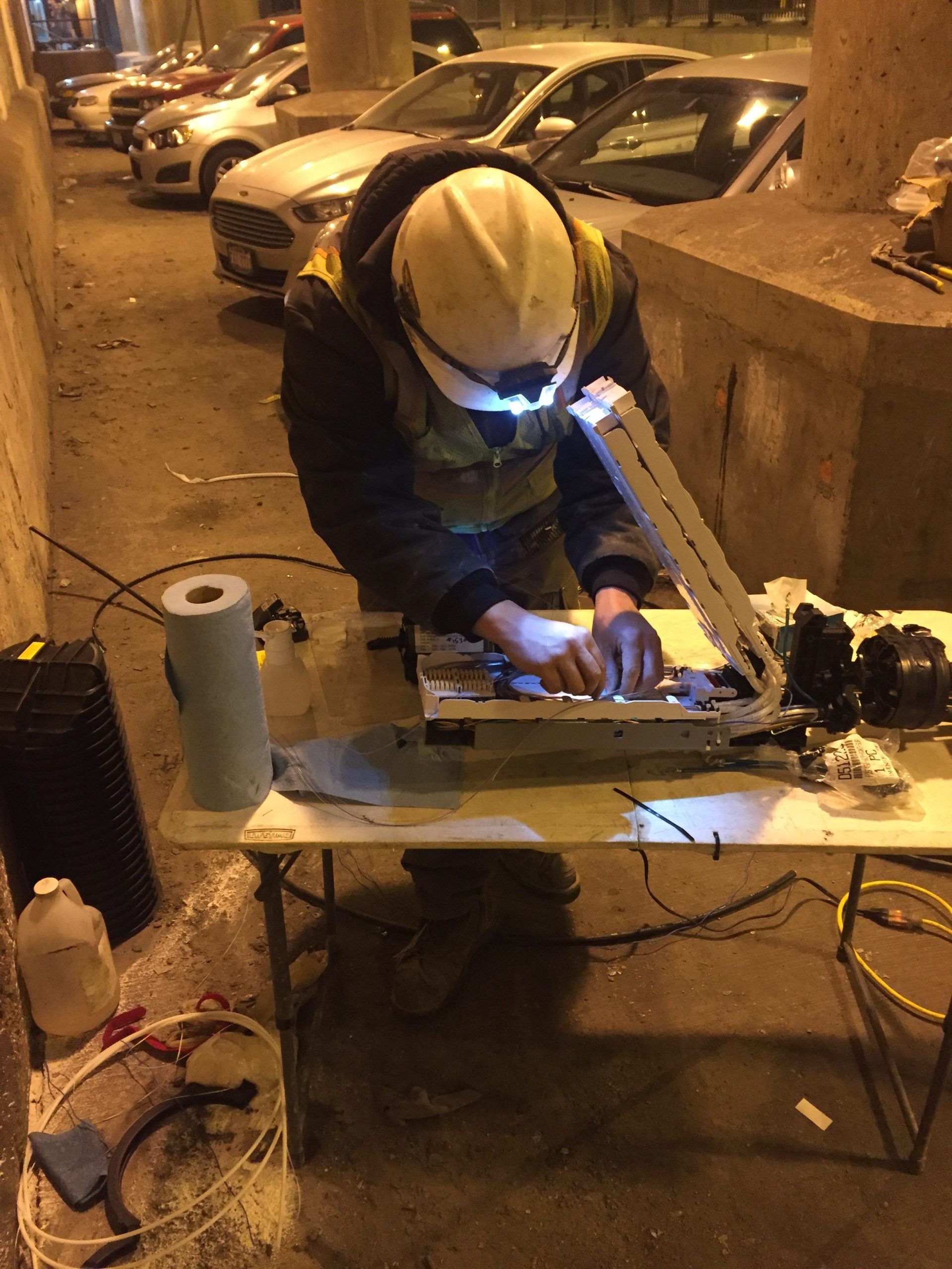 A man wearing a hard hat is working on a piece of equipment on a table.