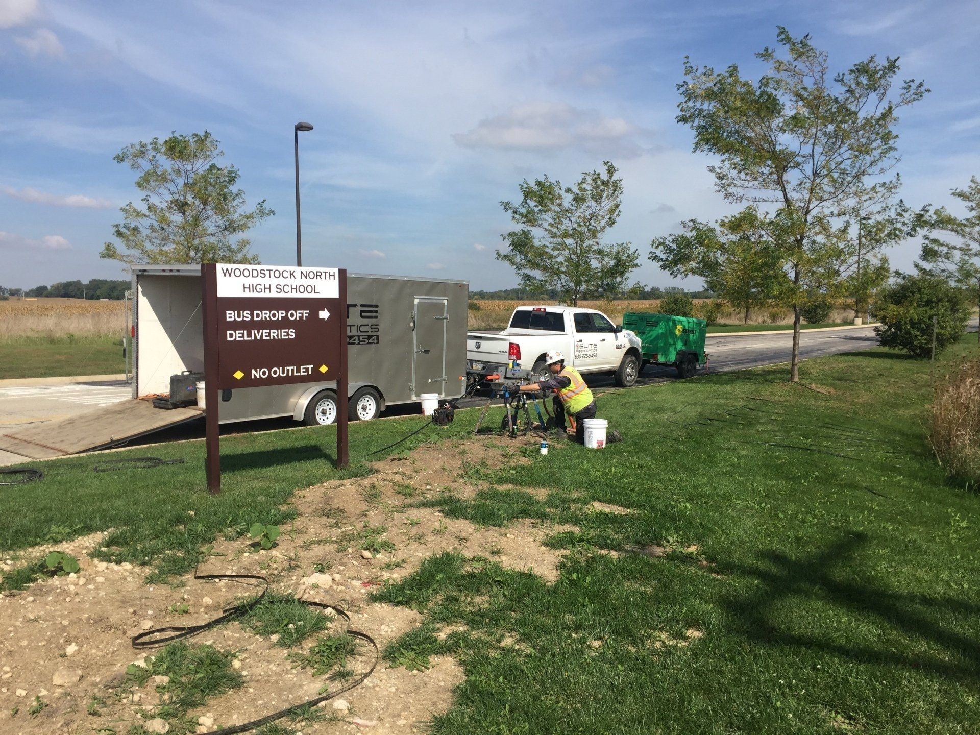 A trailer is parked in a grassy field next to a sign.