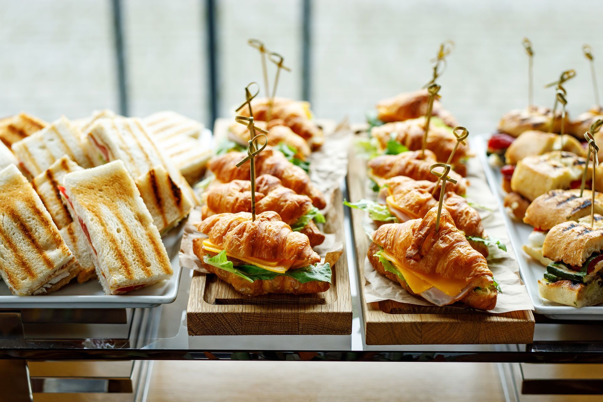 A buffet table filled with sandwiches and croissants on skewers.