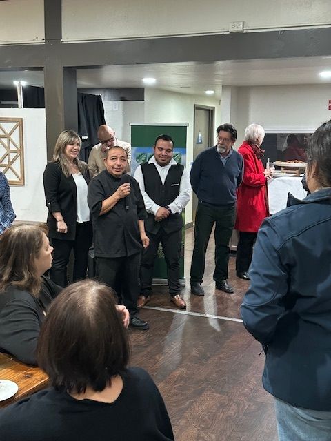 A group of people are standing in a room talking to each other