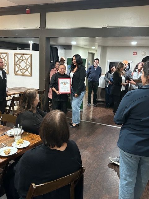 A woman is holding a certificate in front of a group of people.