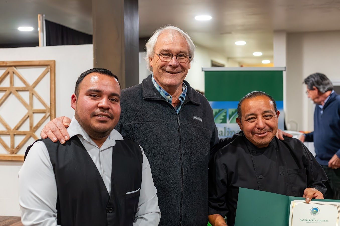 Three men are posing for a picture together in a room.