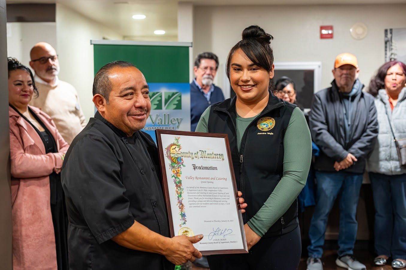 A man is giving a certificate to a woman in front of a group of people.