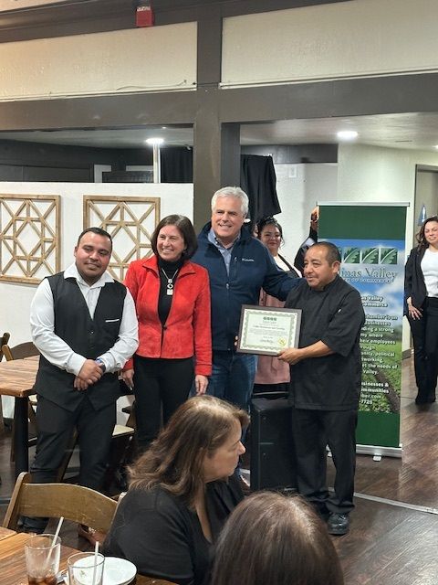 A group of people are standing around a man holding a certificate.