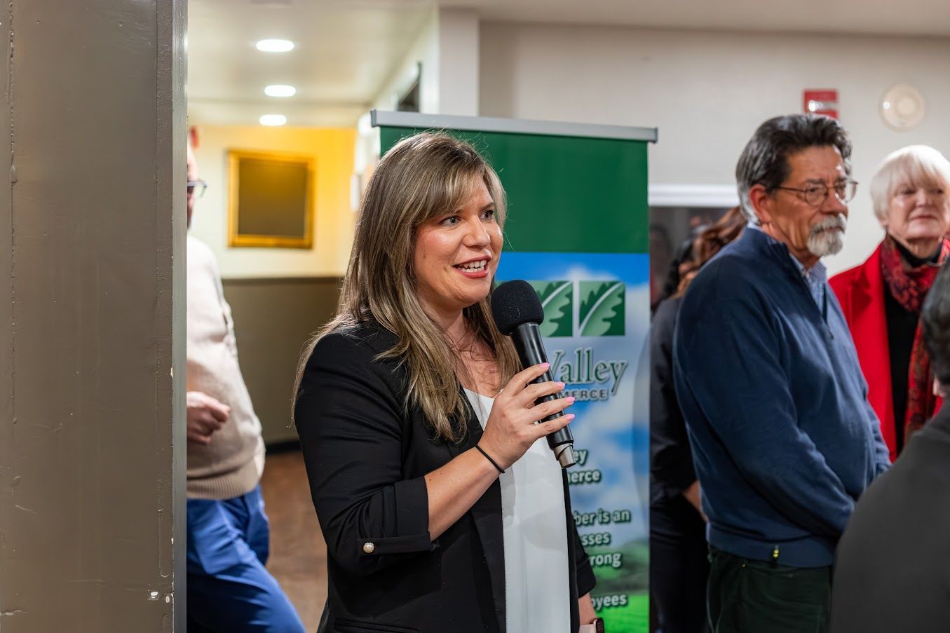A woman is holding a microphone in front of a group of people.