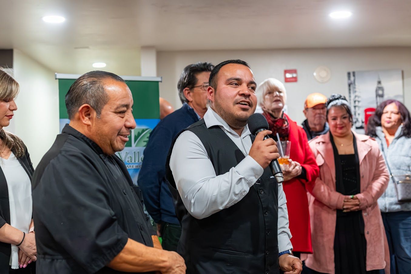 A man is holding a microphone in front of a group of people.