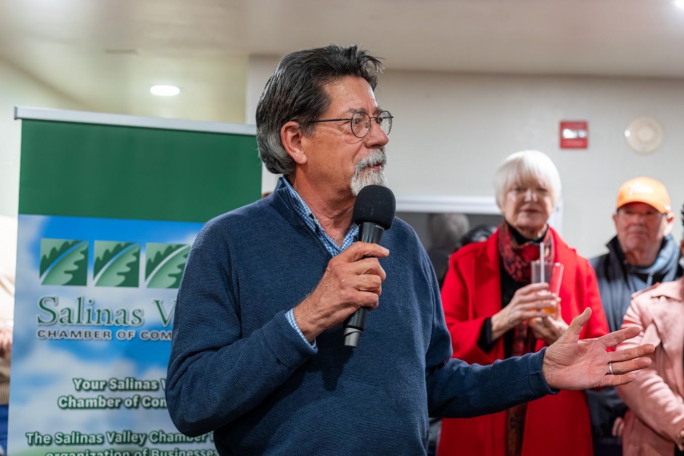 A man is holding a microphone and talking to a group of people.