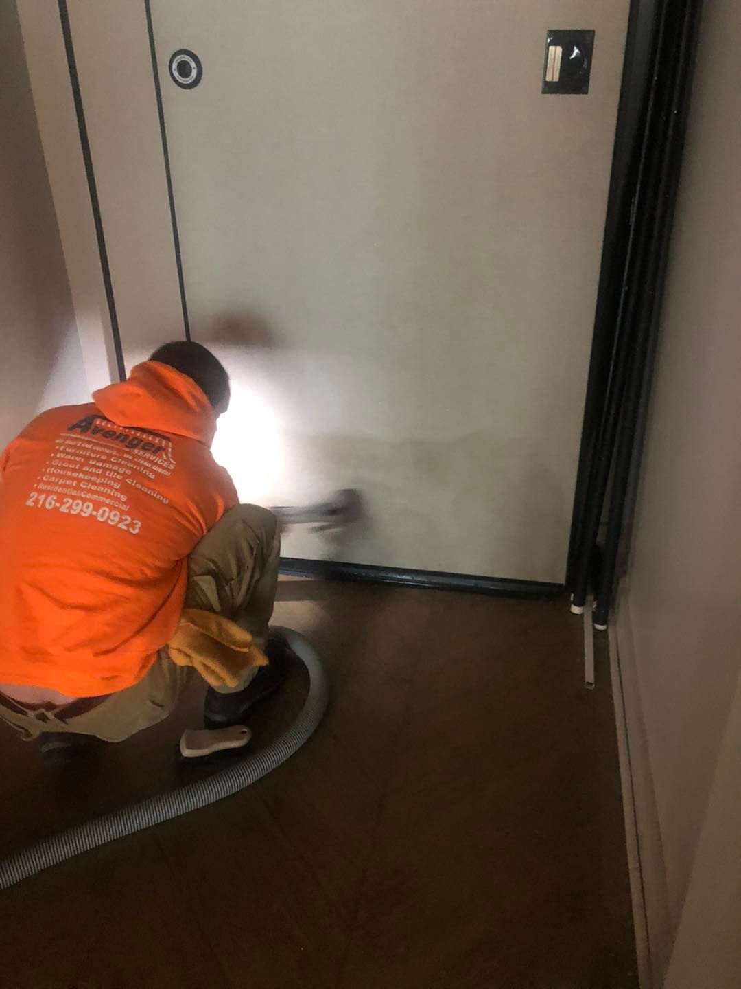 A man is cleaning a door with a vacuum cleaner.
