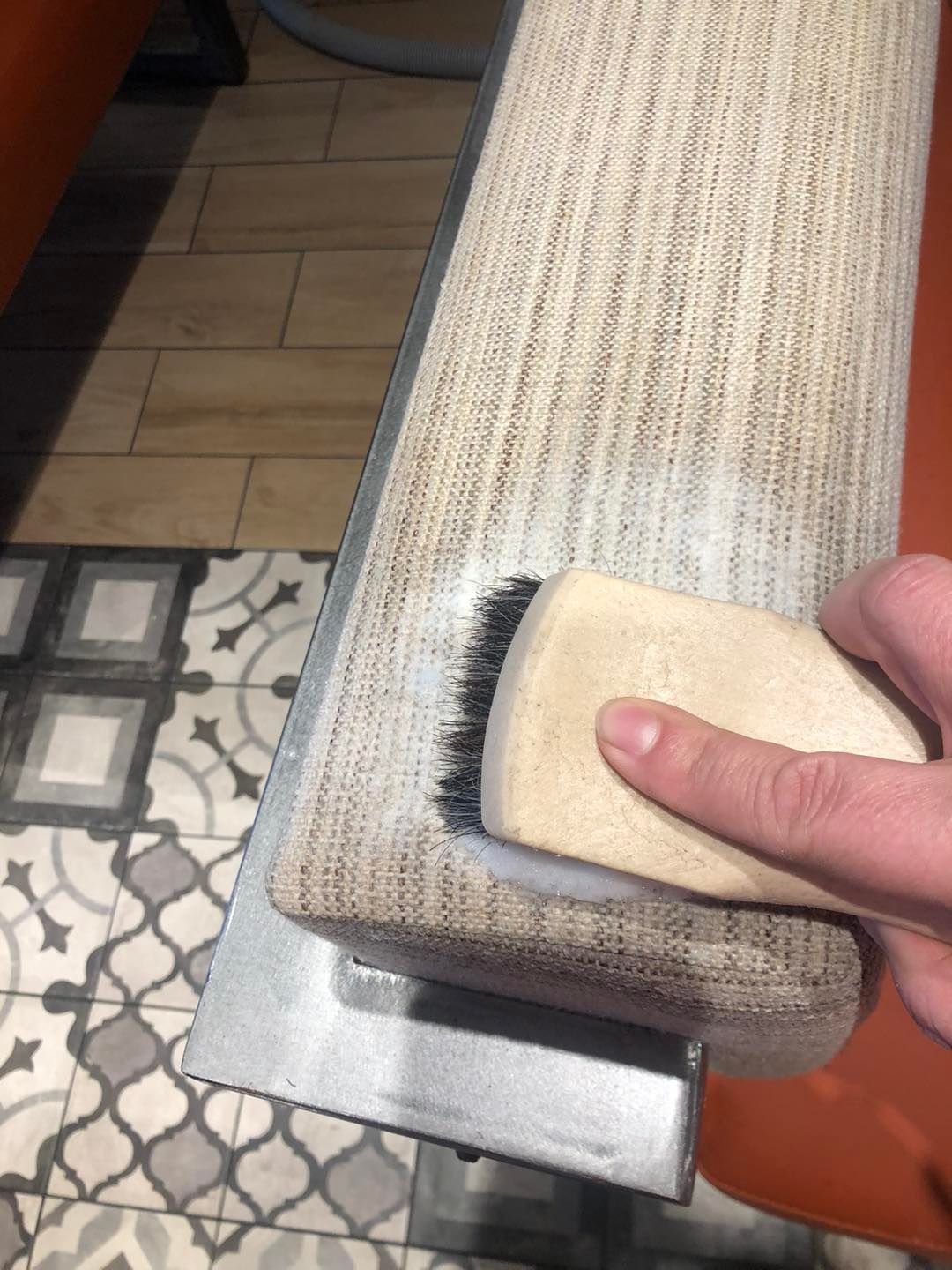 A person is cleaning a chair arm with a brush.