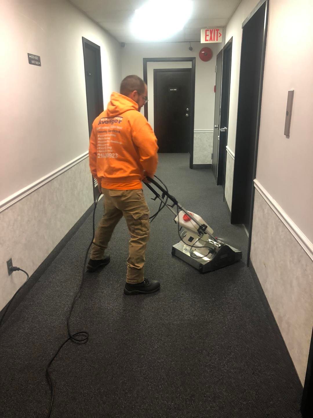A man is cleaning a hallway with a vacuum cleaner.