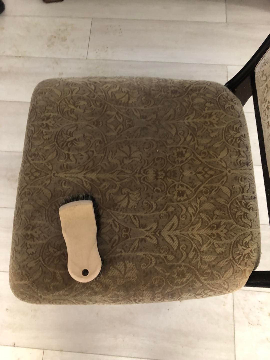 A wooden brush is sitting on top of a chair cushion.