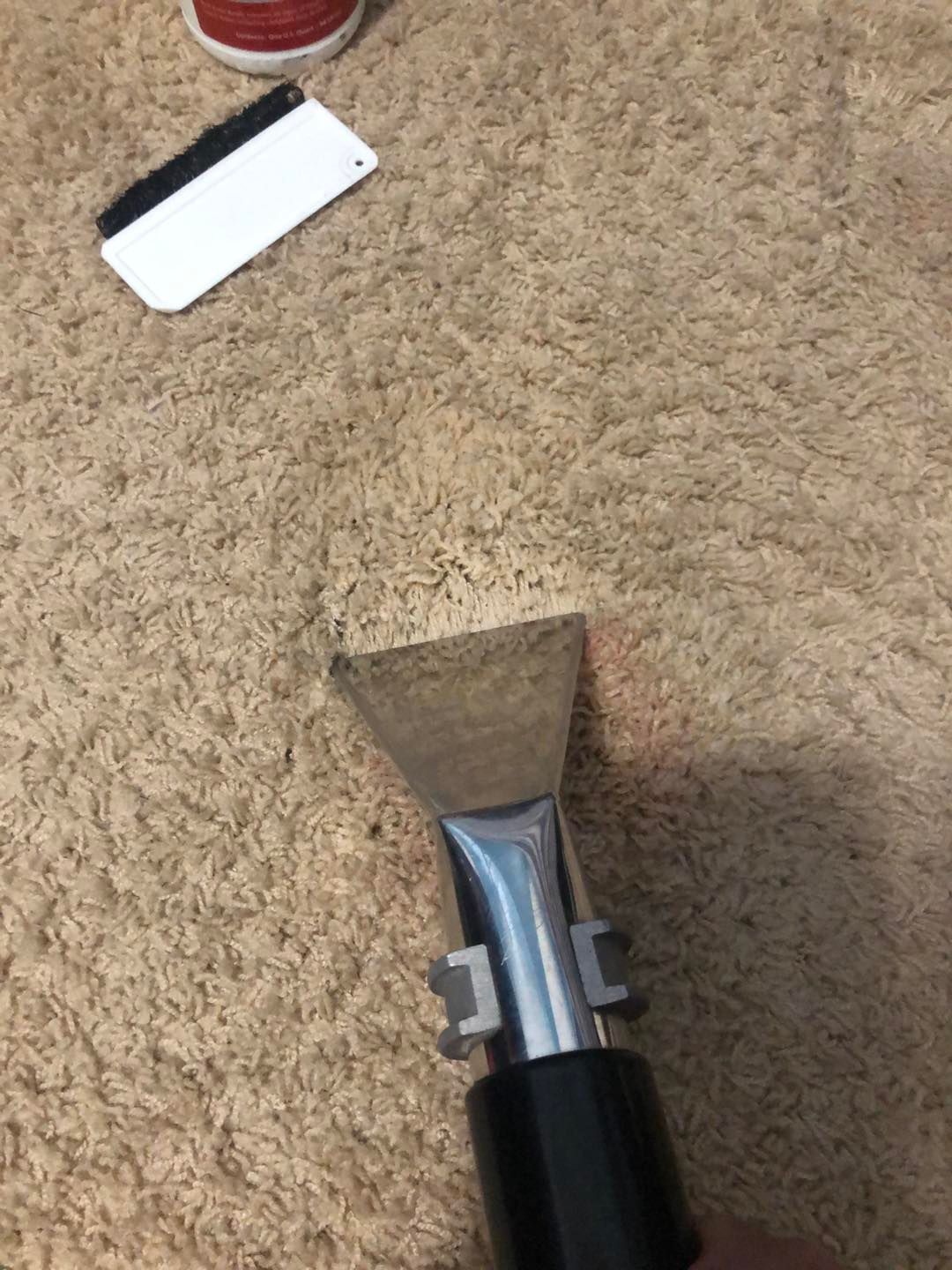 A person is cleaning a carpet with a vacuum cleaner.