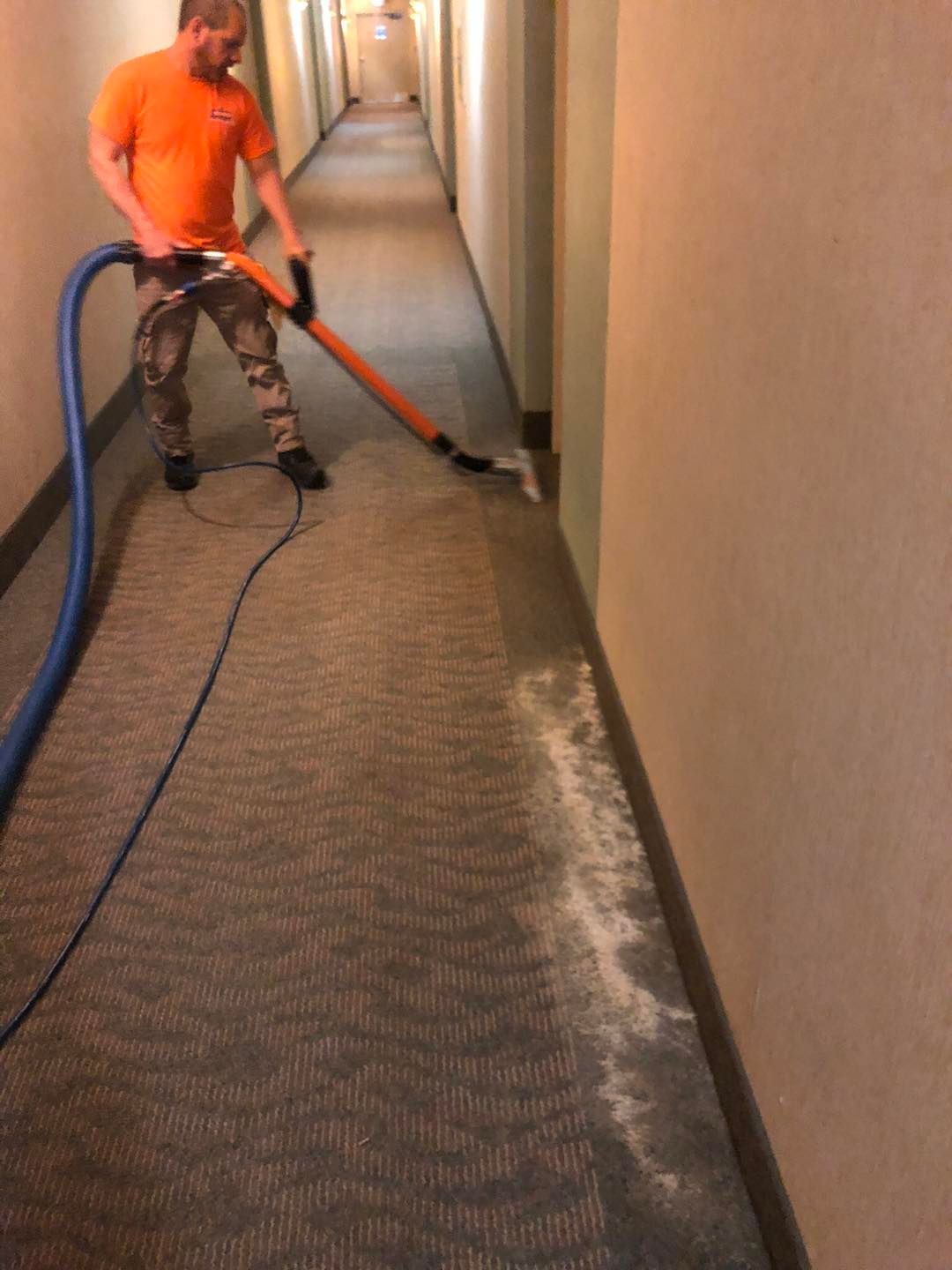 A man is cleaning a hallway with a vacuum cleaner