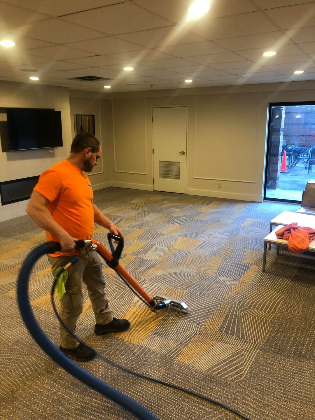 A man is using a vacuum cleaner to clean a carpet in a room.
