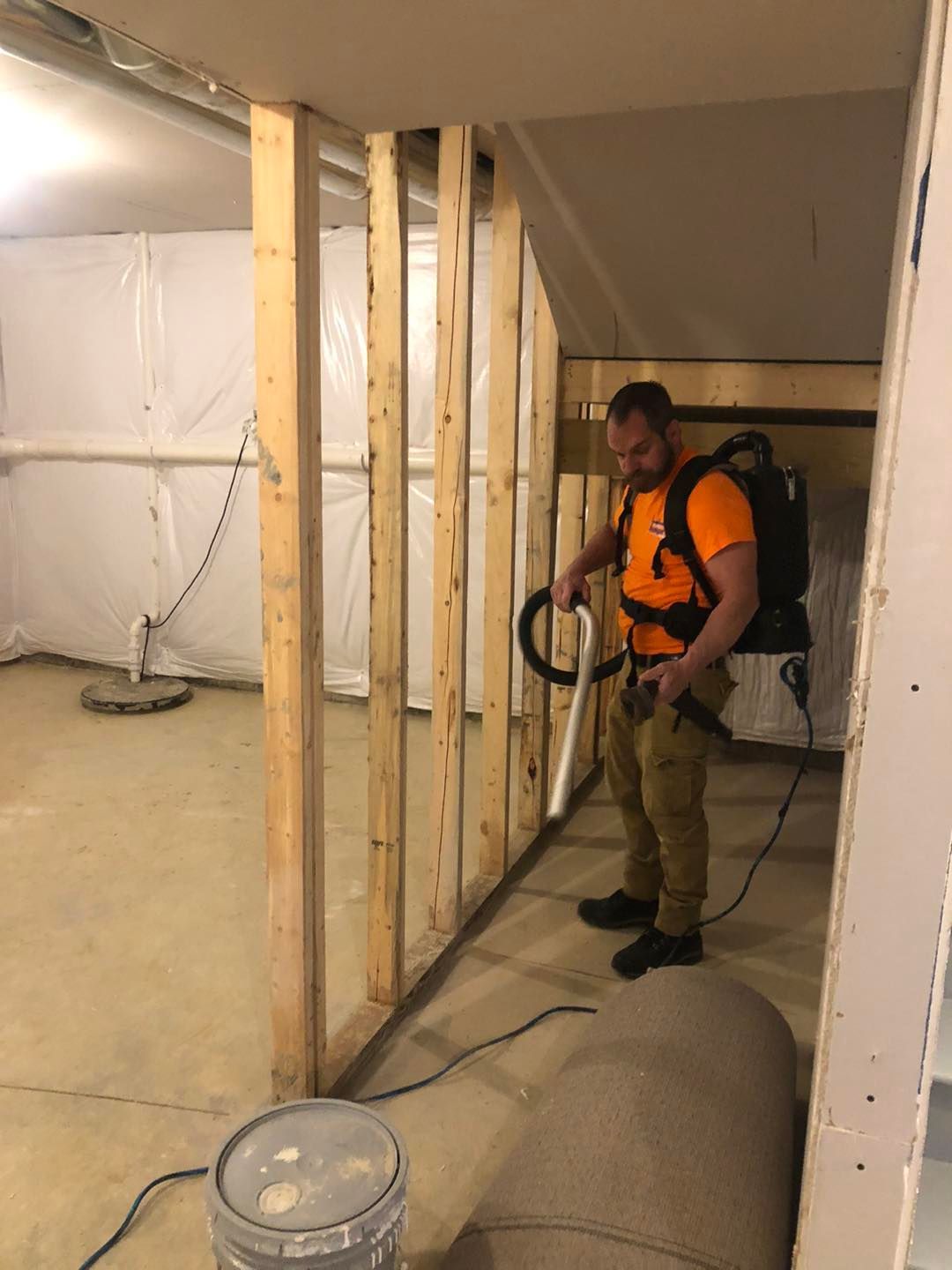 A man is standing in a basement holding a vacuum cleaner.