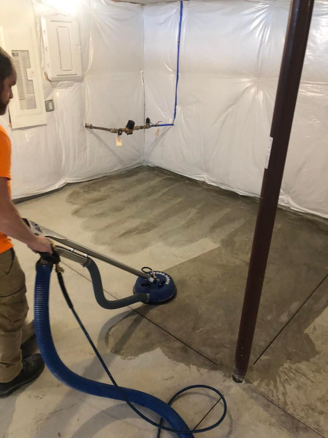 A man is using a vacuum cleaner to clean a basement floor