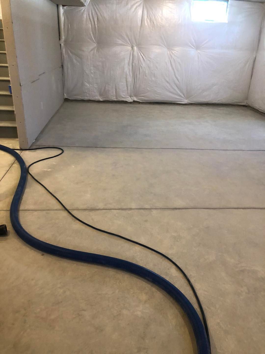A vacuum cleaner is sitting on the floor of a basement.