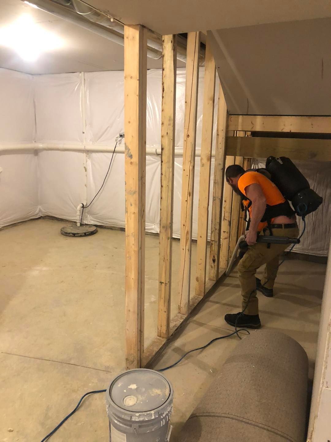 A man is using a vacuum cleaner to clean a basement.