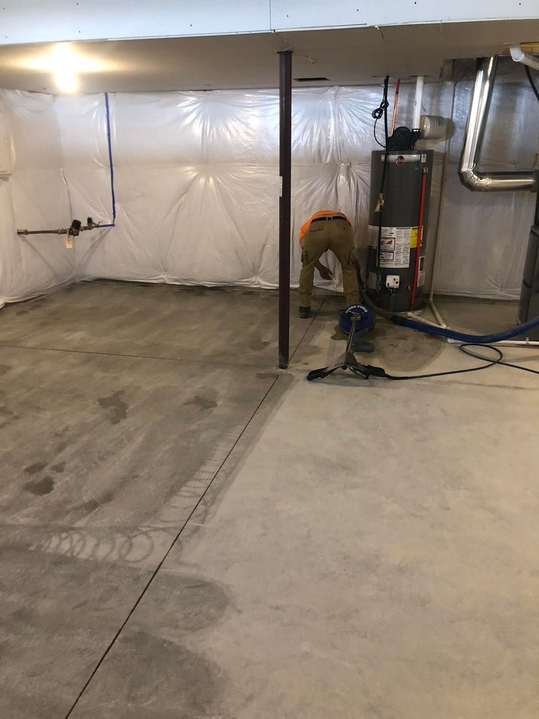 A man is working in a basement with a vacuum cleaner.