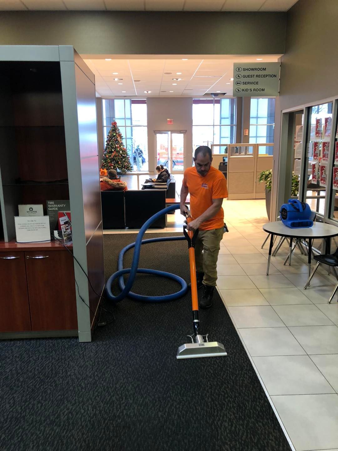 A man is cleaning a carpet with a vacuum cleaner.