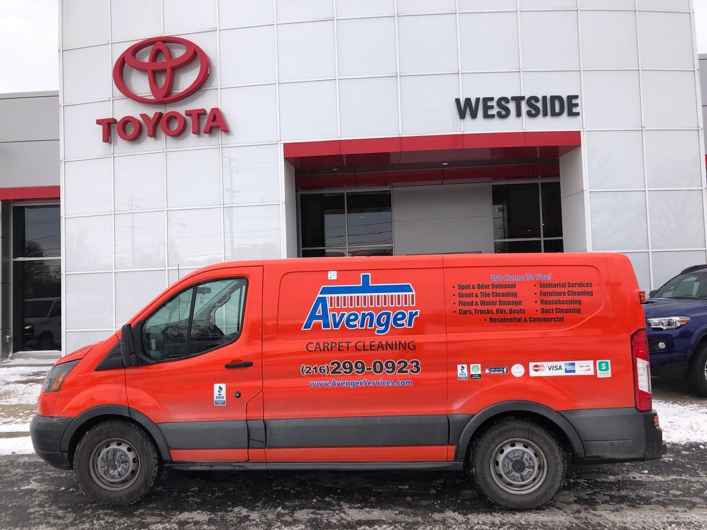 A red van is parked in front of a toyota dealership