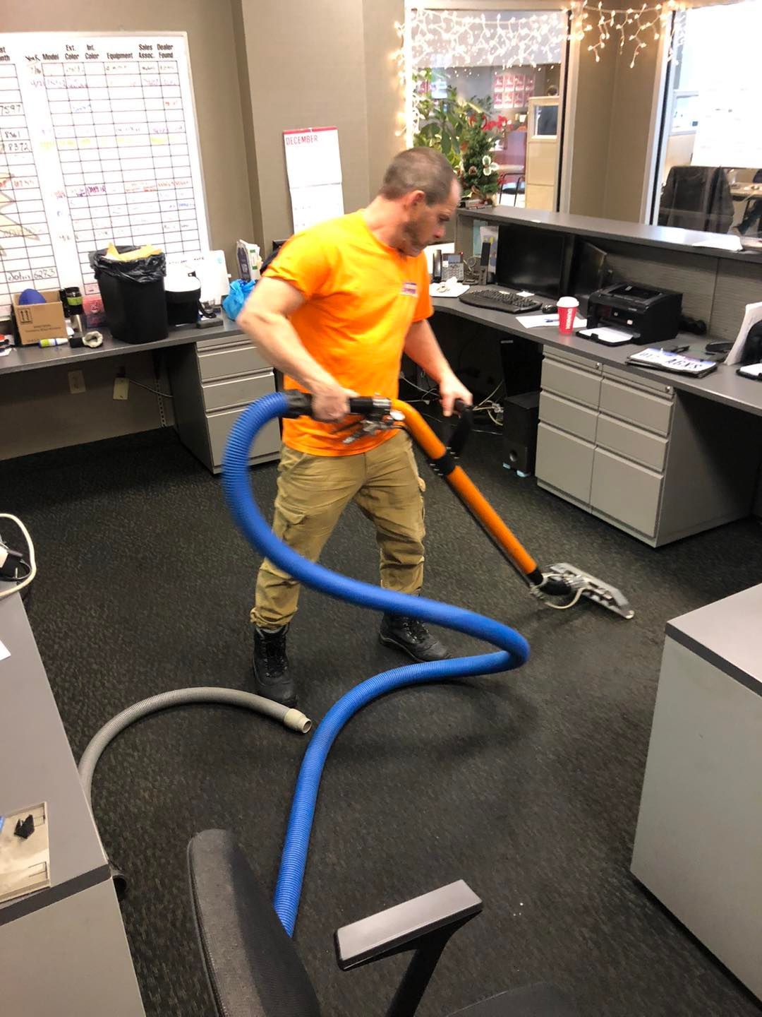 A man is cleaning the floor of an office with a vacuum cleaner.