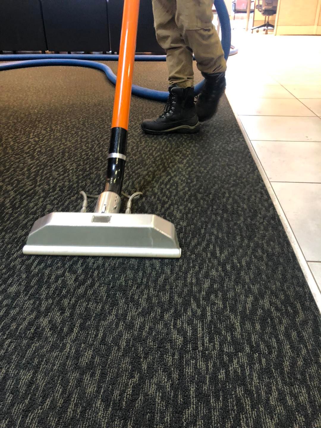 A person is using a vacuum cleaner to clean a carpet.
