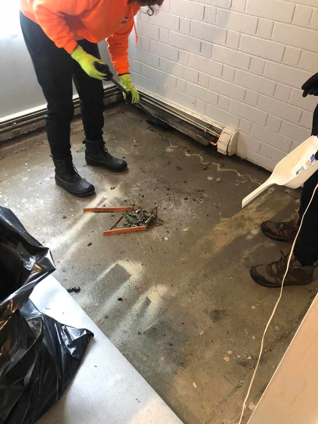 A person is cleaning the floor with a pair of pliers.