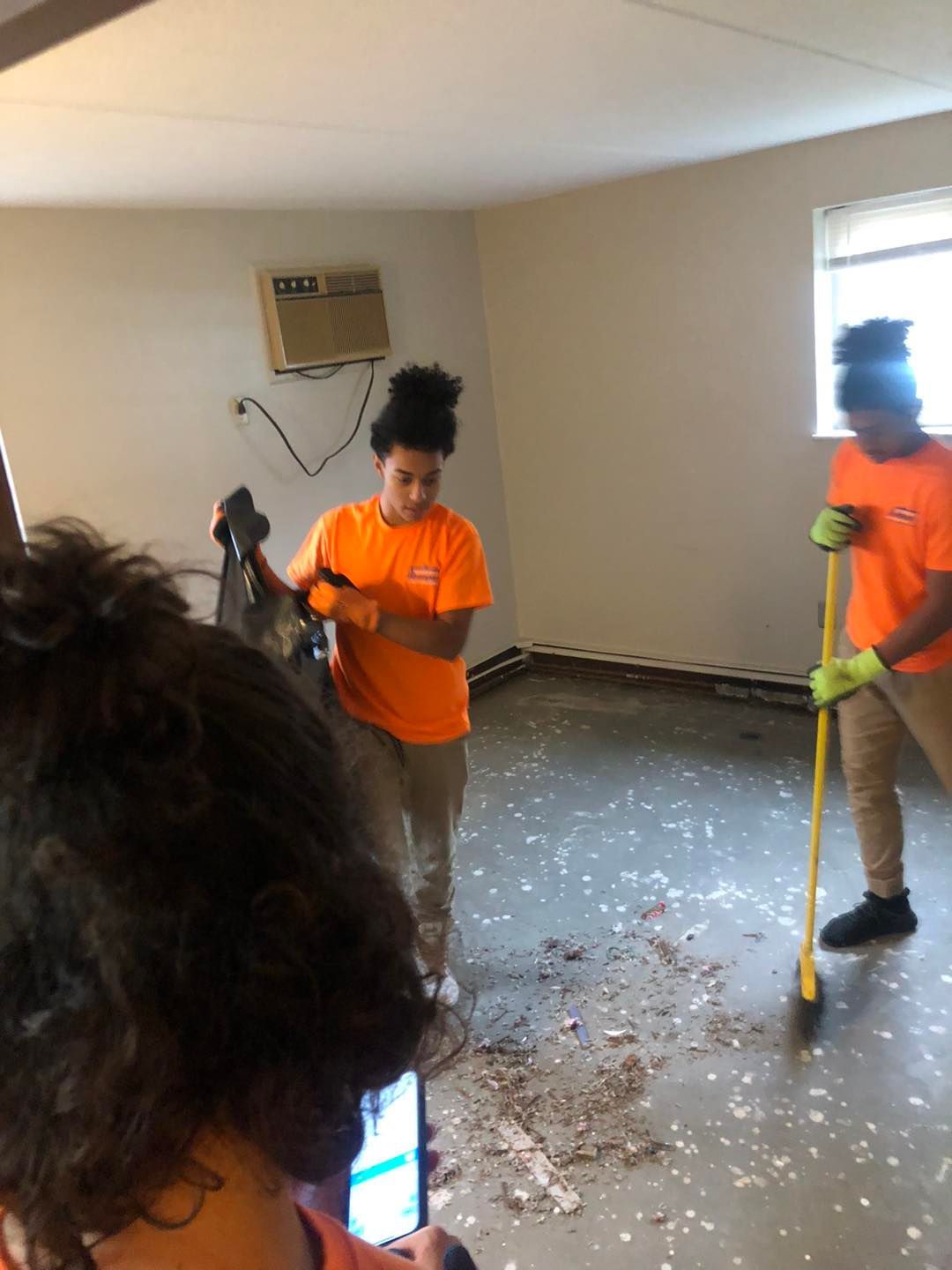 A woman is taking a picture of two people cleaning a room.