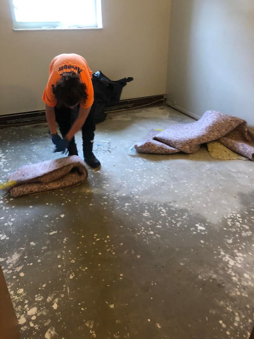 A person wearing an orange shirt working on water damage restoration