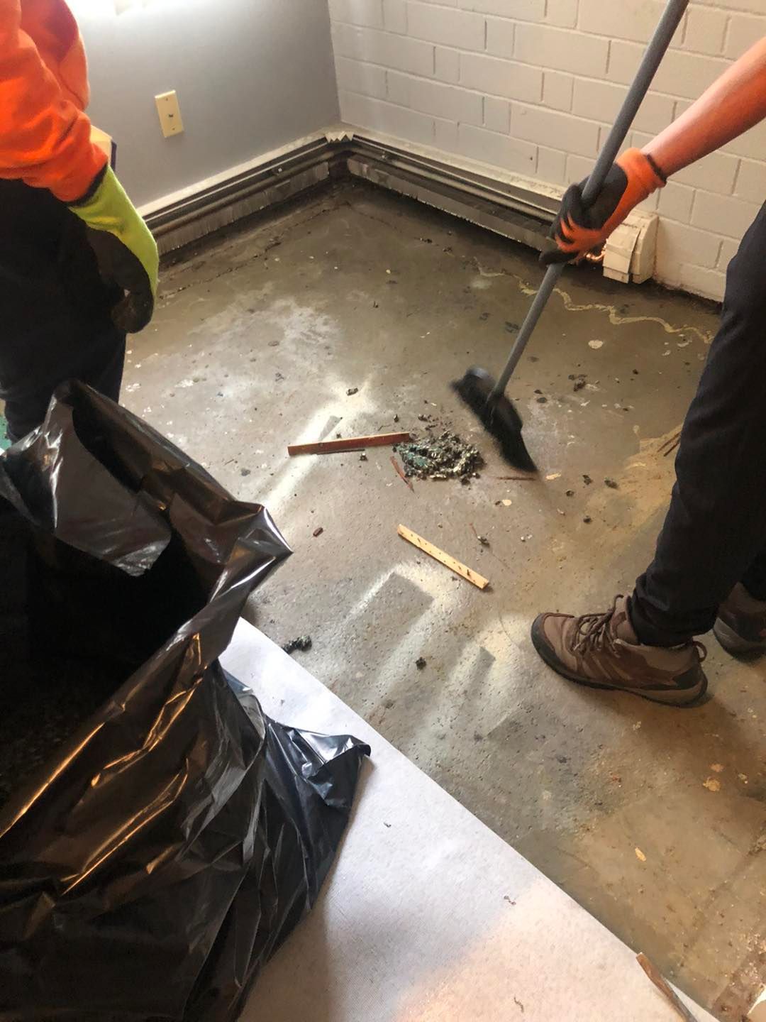A person is using a broom to clean a dirty floor