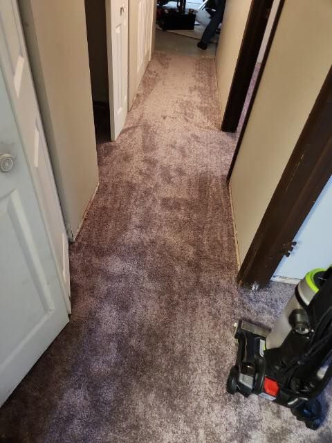 A vacuum cleaner is sitting on the floor in a hallway next to a door.