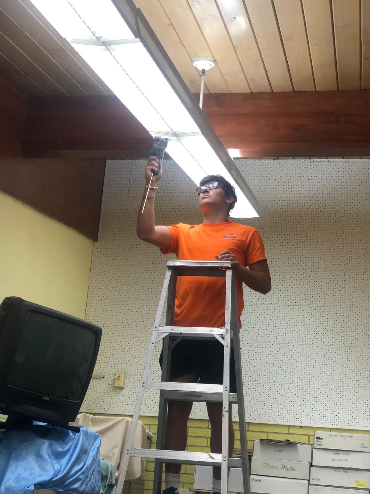 A man standing on a ladder with a drill in his hand