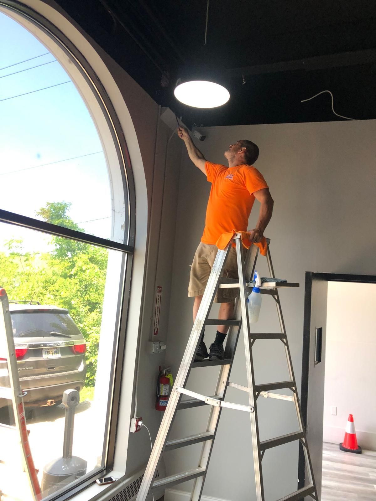 A man standing on a ladder in front of a fire extinguisher