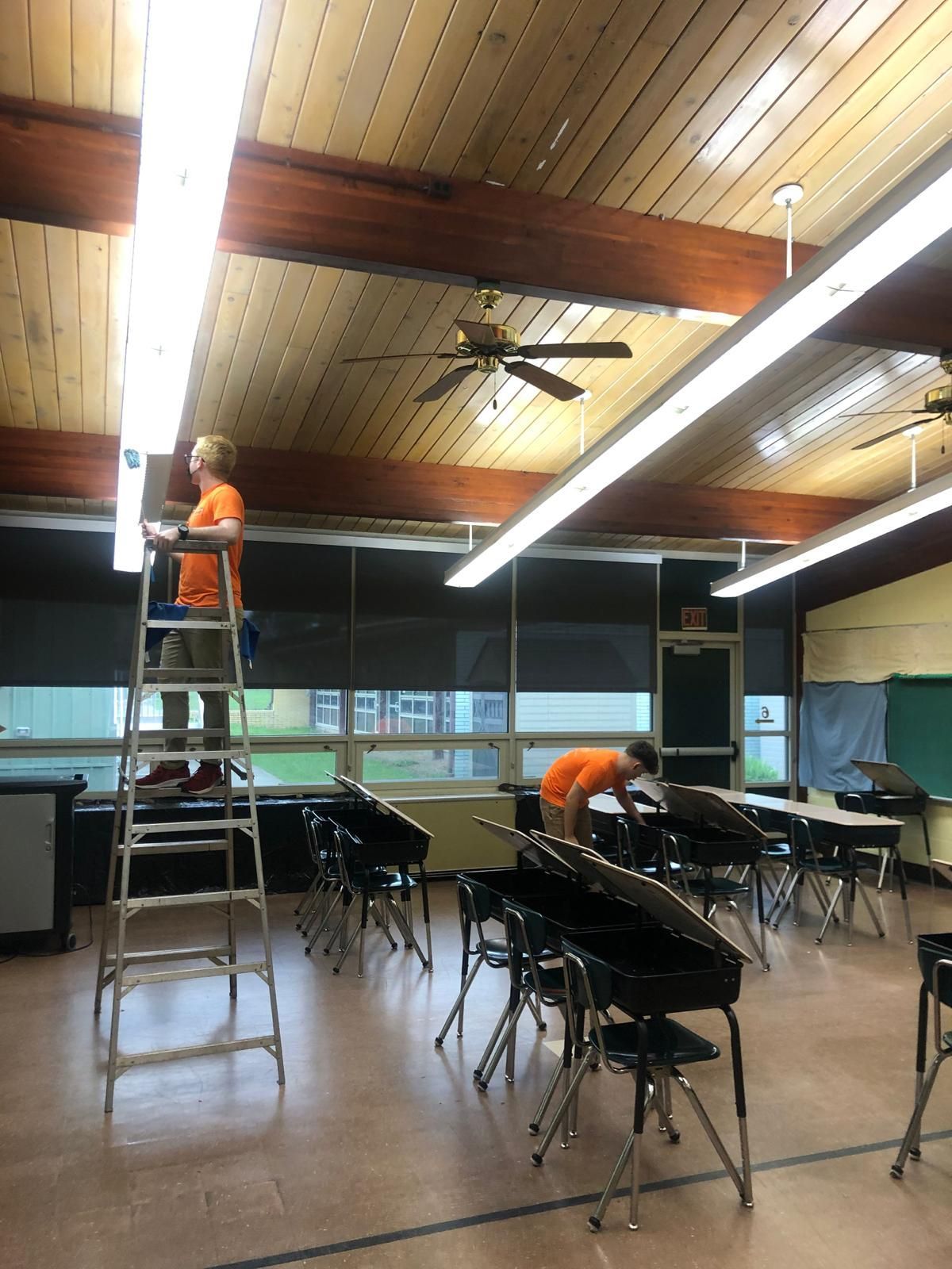 A man on a ladder in a room with a sign that says exit