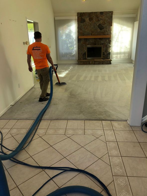 a man wearing an orange shirt cleaning a carpet