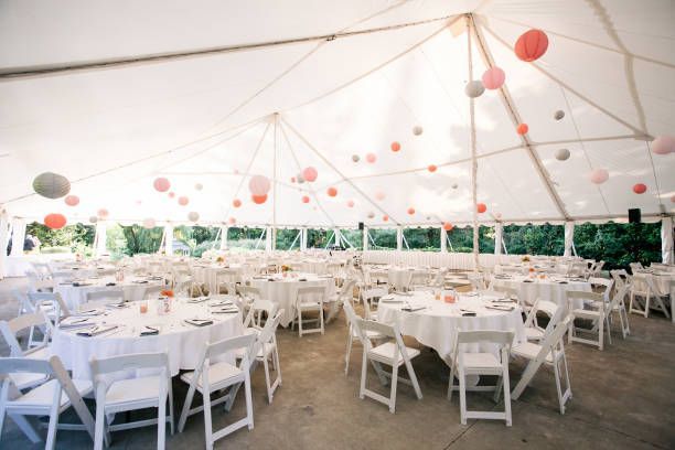 A large tent with tables and chairs set up for a wedding reception.