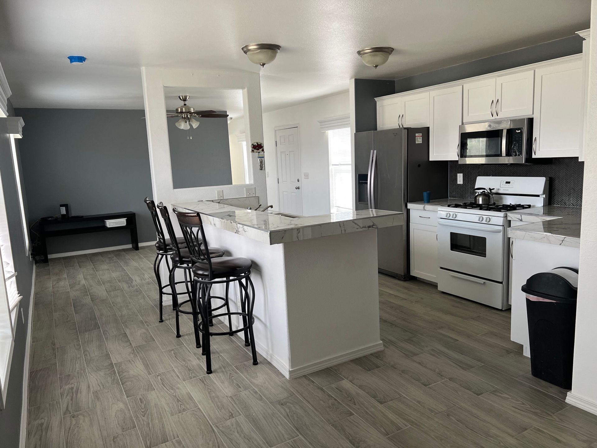 A kitchen with a stove , refrigerator , microwave and stools.