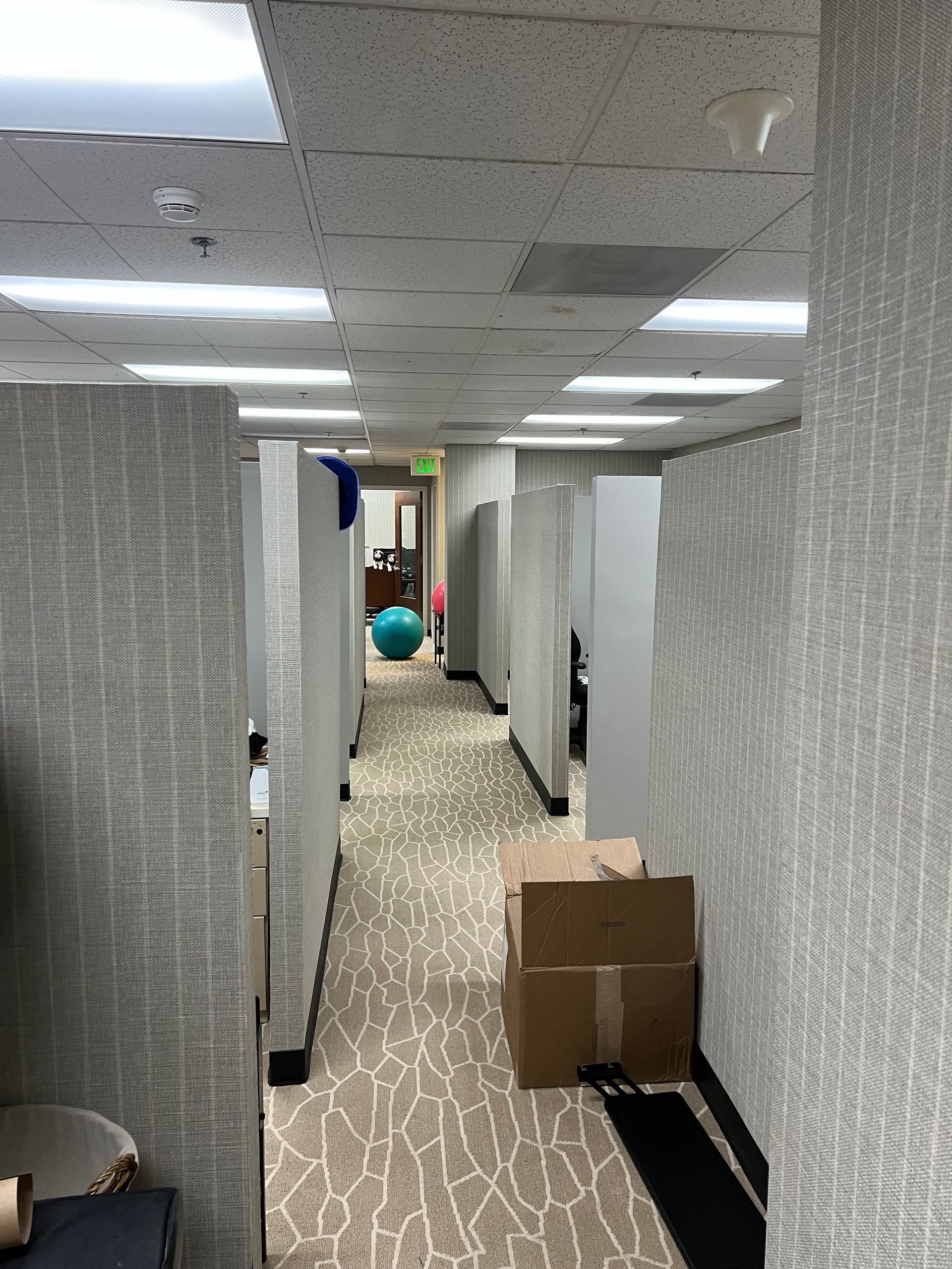 A hallway in an office with cubicles and a box on the floor.