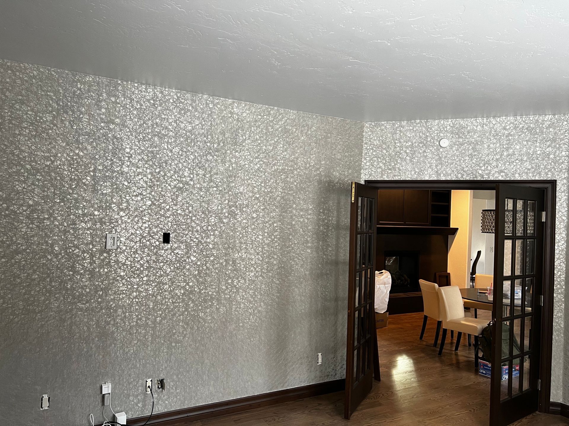 A living room with a silver wall and a dining room in the background.