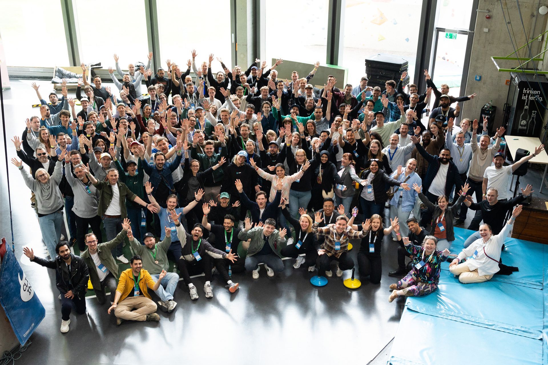 A large group of people are posing for a picture with their hands in the air