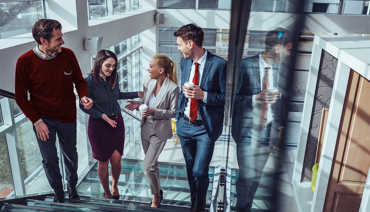 A group of business people are walking down stairs in an office building.