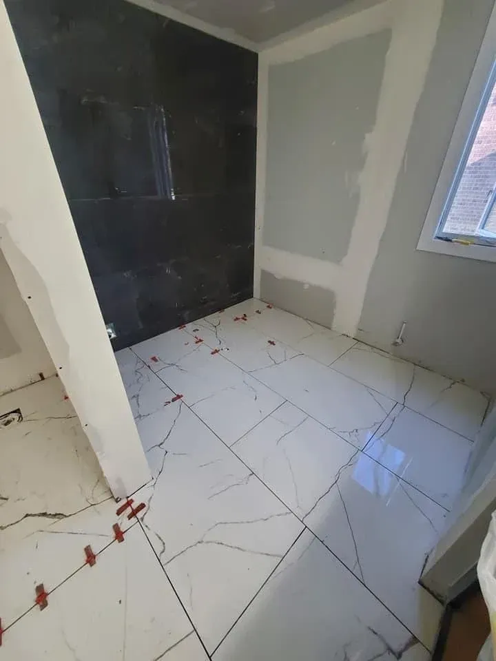 A room with white tiles on the floor and a black wall.