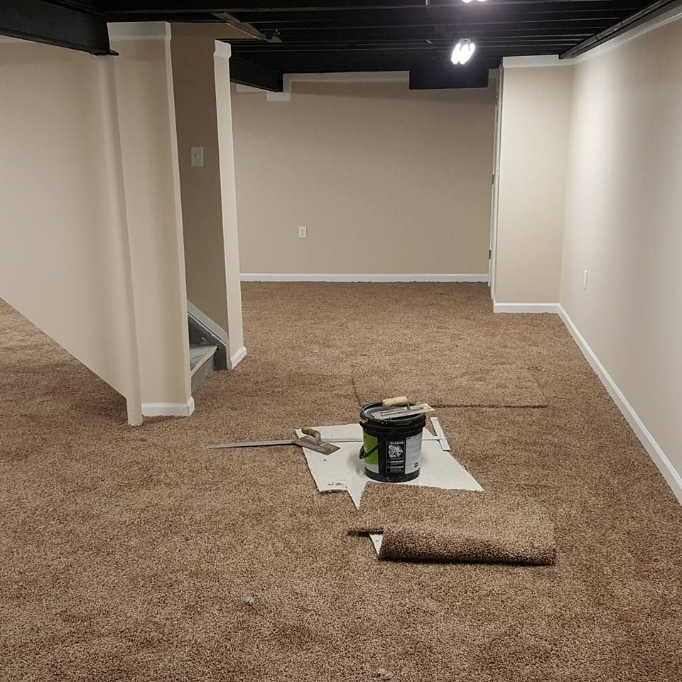 An empty basement with a bucket of paint on the floor