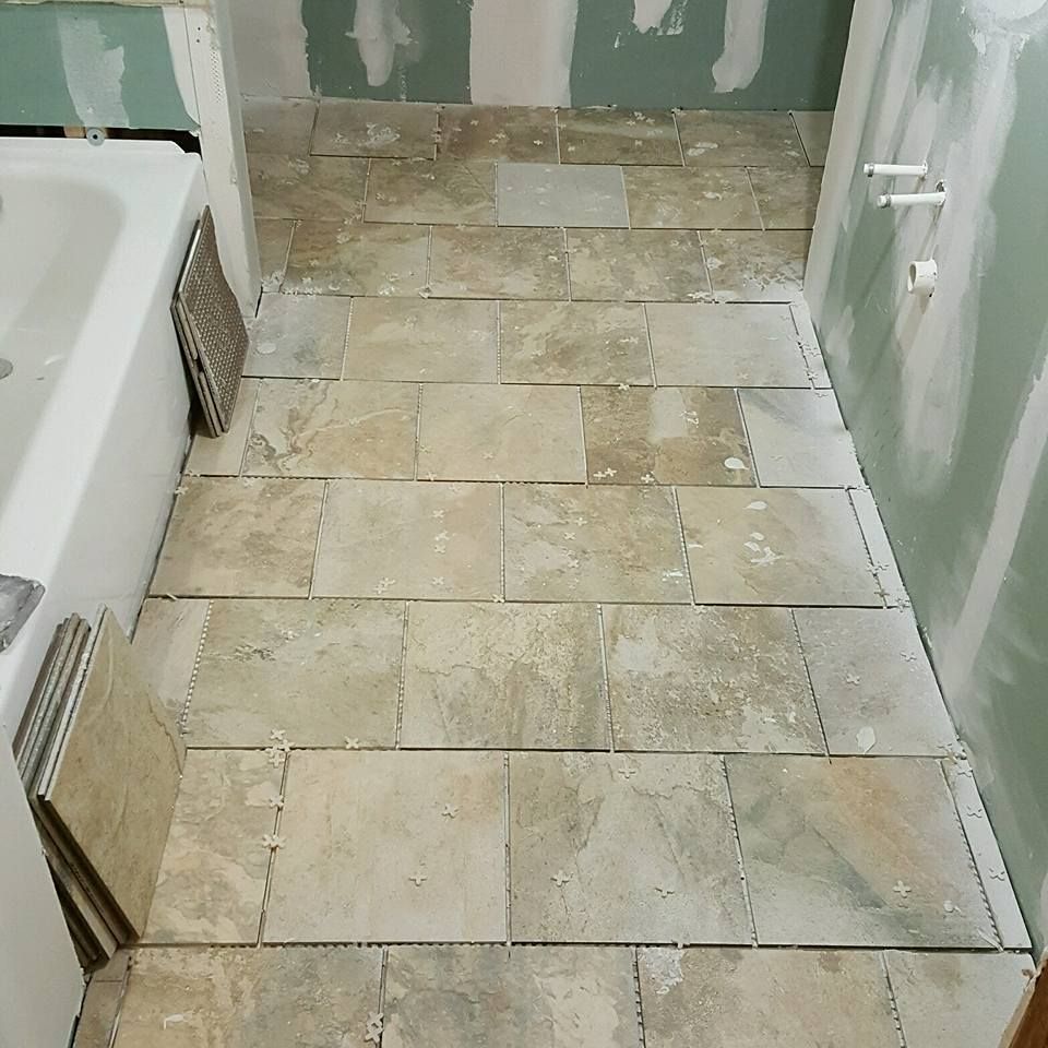 A tiled floor in a bathroom next to a bathtub
