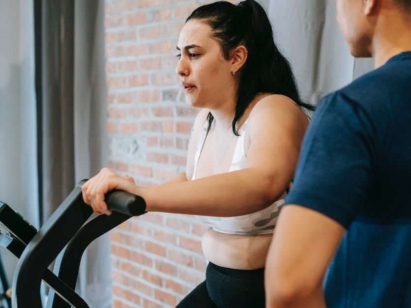 A woman is riding an exercise bike next to a man in a gym.