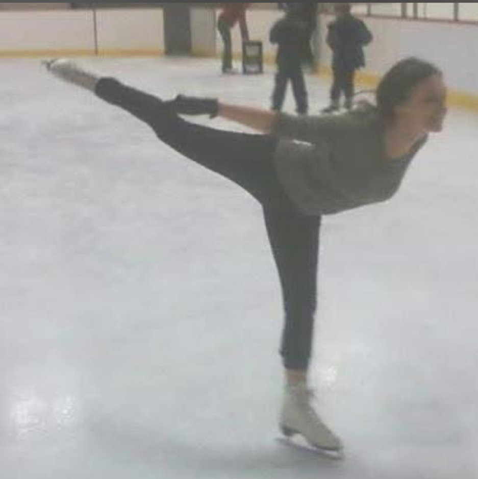Woman smiles, looking at camera. Wearing white blouse. Bedroom setting with bed in background.